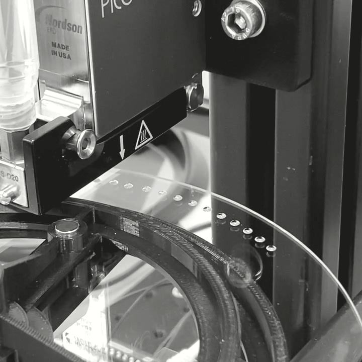 Close-up of a precision dispensing head on a rotary assembly fixture